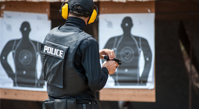 Policjant w Kamizelce Kuloodpornej Trenuje Strzelanie do Celu.